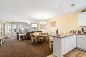 A spacious living area with a dining table, chairs, a sofa, and a kitchen with a bar counter.