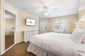 Une chambre à coucher avec un lit, une commode, un téléviseur et un ventilateur de plafond.