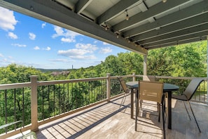 A covered outdoor area with a table and chairs, overlooking a dense forest. - Near Silver Dollar City, Lake View Condo with Complimentary Daily Tickets (Branson)