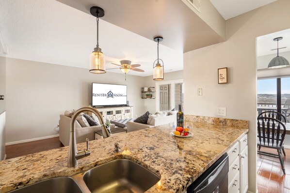 A kitchen with granite countertops, stainless steel sink, and pendant lighting. - Near Silver Dollar City, Lake View Condo with Complimentary Daily Tickets (Branson)