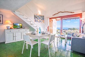 A dining area with a white table, chairs, and a painting above. - Le Dalie With Shared Pool, Marinella, Italy (Marinella)
