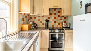 Une cuisine avec des meubles de rangement en bois, un évier, une cuisinière et un four à micro-ondes.