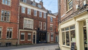 Une vue de rue présentant une rangée de bâtiments traditionnels en briques, dont l’un possède une devanture de magasin et l’autre une fenêtre visible.