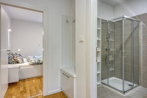 Une salle de bain moderne dotée d’une douche à parois de verre, d’un banc intégré avec espace de rangement et de toilettes apparentes.