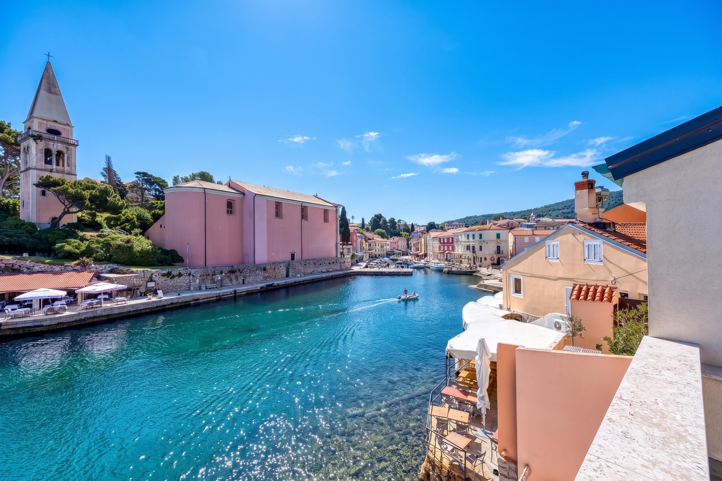 Une ville côtière où le ciel est d’un bleu éclatant, le port est calme et les bâtiments présentent une architecture traditionnelle.
