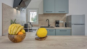 Een moderne keuken met lichtblauwe kastjes, een houten aanrechtblad en een fruitschaal met bananen en een sinaasappel.
