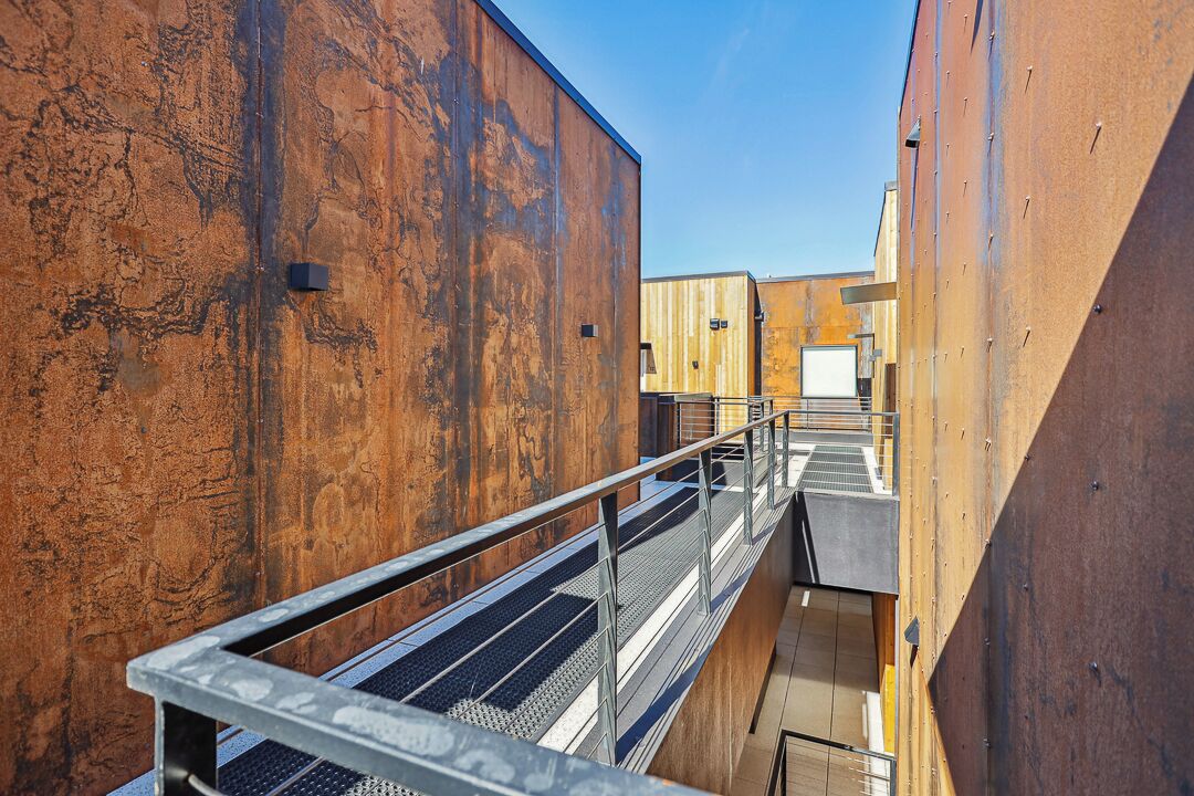 A narrow corridor with metal railings and a staircase leading to a higher level.