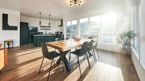 A modern kitchen with a wooden dining table and chairs, large windows with a view of the outdoors, and a hanging light fixture. - One-bedroom honeymoon penthouse, Mt Hood views, downtown White Salmon, suite 16 (White Salmon)