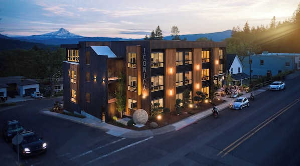 A modern building with a prominent 'IC' sign, a landscaped front yard, and a mountain in the background.