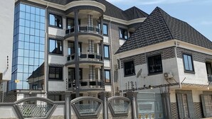 A multi-story residential building with a balcony, large windows, and a gated entrance. - DJ Villa Your Premium Stay-NS24 (Tema Community 25, Accra-Dawhenya)