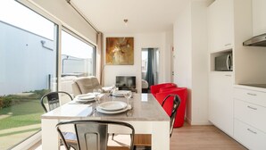 A modern kitchen with a dining table set for four, a red chair, and a view of the outdoors.