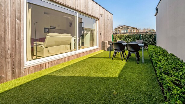 A modern house with a large sliding glass door leading to a living area with a sofa and chairs.