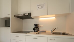 Una kitchenette compacta con estufa, cafetera y pileta.