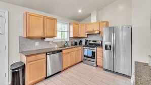 A modern kitchen with wooden cabinets, stainless steel appliances, and a granite countertop. - 4BR Family Getaway w/ King Bed + 5 TVs, Mins to DC/OldTown,Gameroom,Pet Friendly (Alexandria)