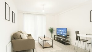 A modern living room with a sofa, coffee table, TV, and a small dining area. - Not available (Salford)