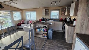Et kompakt køkken med spiseplads, indbygget ovn og opholdsområde med sofa og stole.