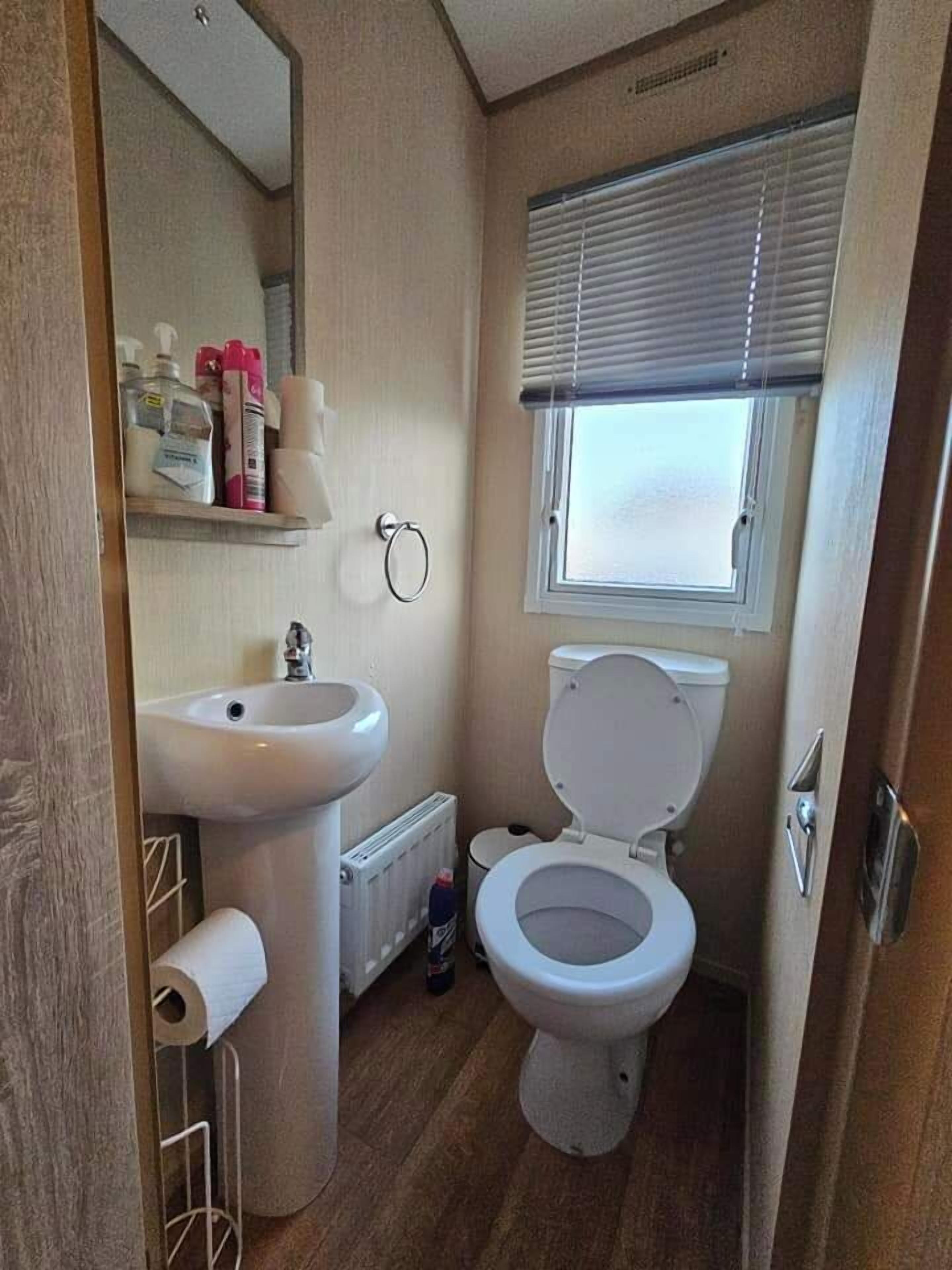 Ein kleines Badezimmer mit Waschbecken, Toilette und Fenster.