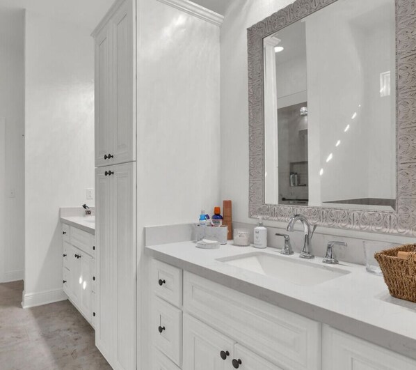 A modern bathroom with a white vanity, a large mirror with an ornate frame, and a sink with two faucets.
