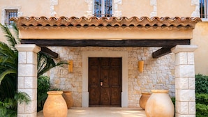 A building with a stone facade, a wooden door, and two large vases in front. - Magnificent Provençal Villa with Swimming Pool and Sea View (Antibes)