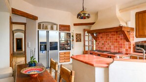 A kitchen with a central island, wooden cabinets, a refrigerator, and a tiled backsplash. - Magnificent Provençal Villa with Swimming Pool and Sea View (Antibes)