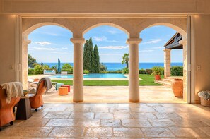 An open patio with a view of a swimming pool and the sea.