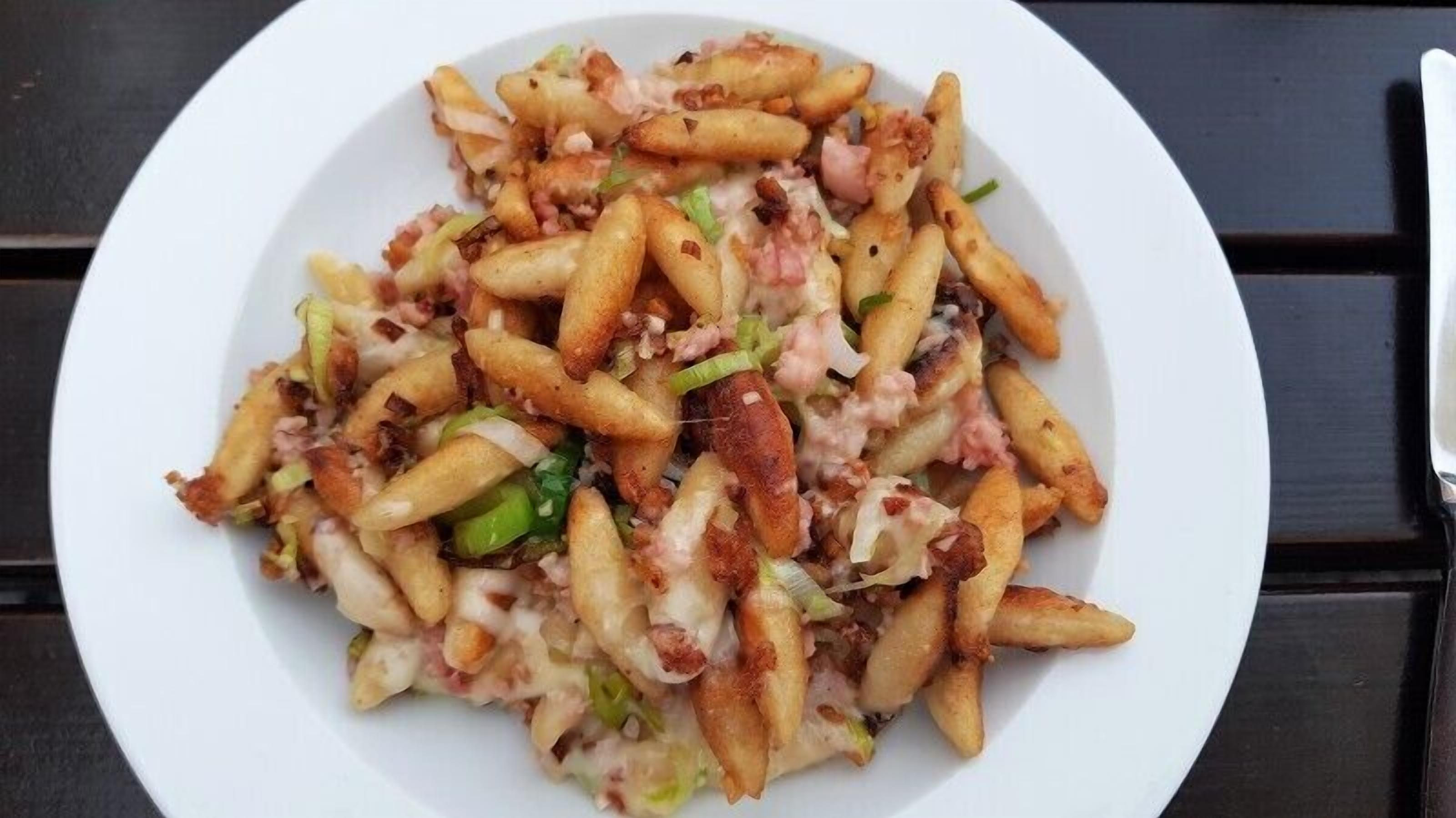 Un plato de comida con papas fritas, queso y tocino.