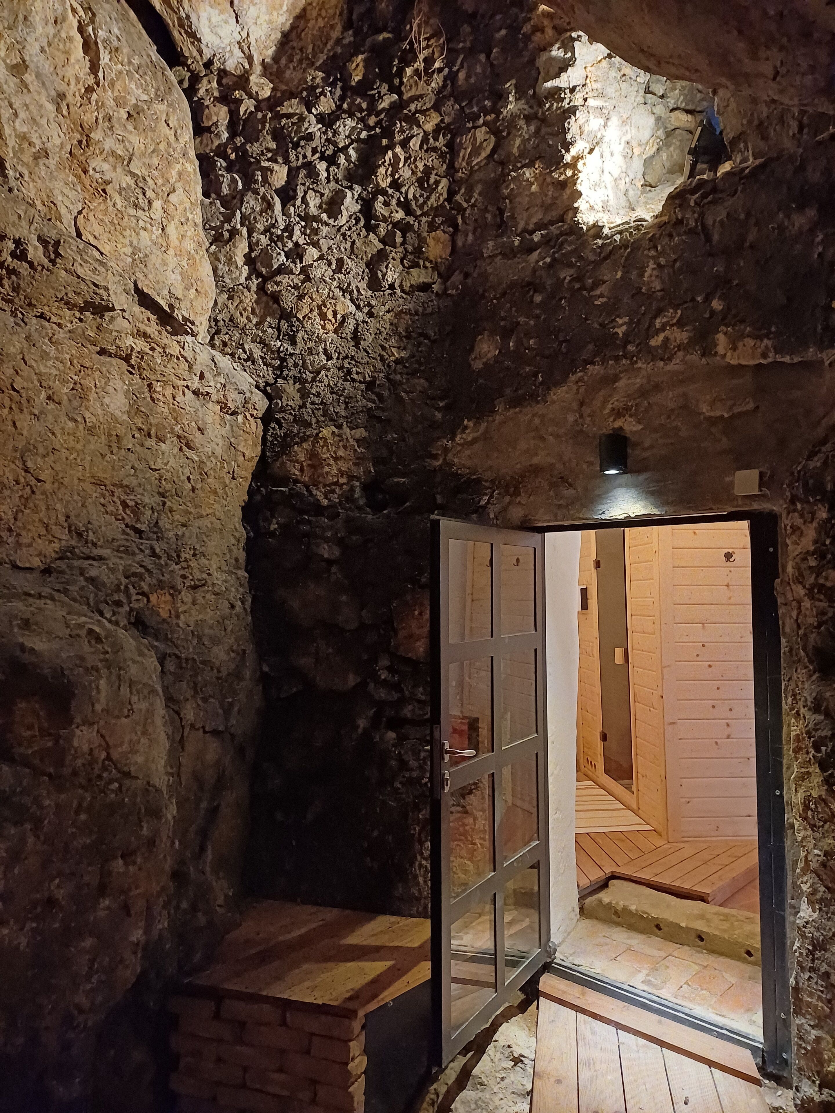 A stone-walled room with a wooden door leading to an interior space.