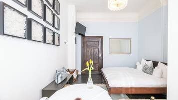 Un dormitorio moderno con cama, mesita de noche y televisor montado en la pared.