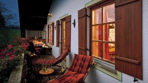 Un espace extérieur accueillant, aménagé avec une table et des chaises, une fenêtre avec des volets et une vue sur l’intérieur.