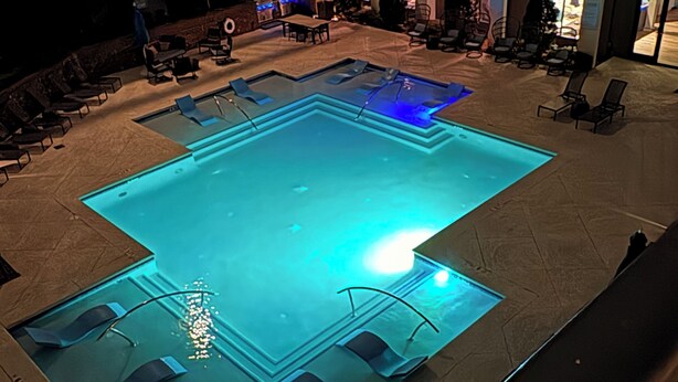 Una piscina al terrat amb gandules i vista a la ciutat.