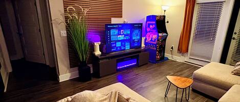 A living room with a flat-screen TV, a ceiling fan, and a potted plant.