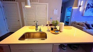 A kitchen with a sink, a potted plant, and a roll of paper towels.