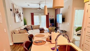 A modern kitchen with a central island, a dining area with a sofa, and a living room with a TV.