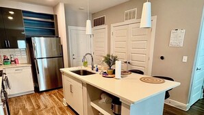A modern kitchen with a central island, stainless steel appliances, and pendant lighting.