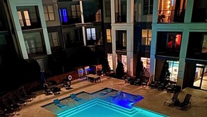 A large indoor swimming pool with multiple lanes, surrounded by lounge chairs and a covered seating area.