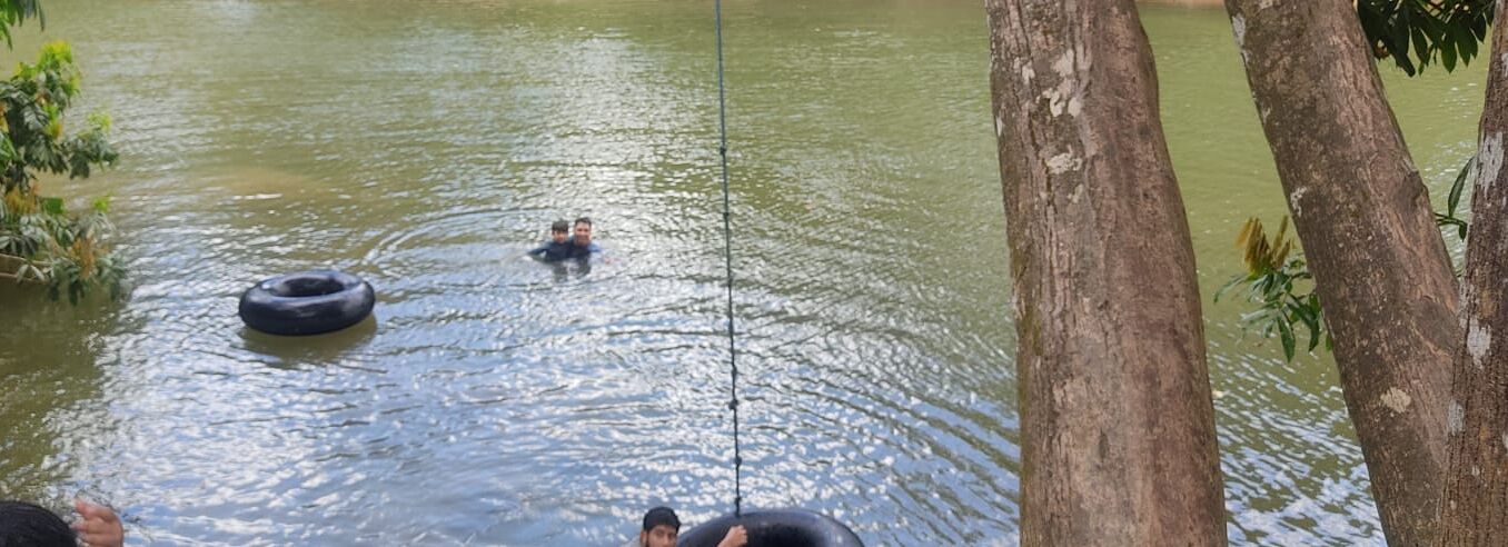 Massa de água com uma pessoa nadando e um tronco de árvore em primeiro plano.