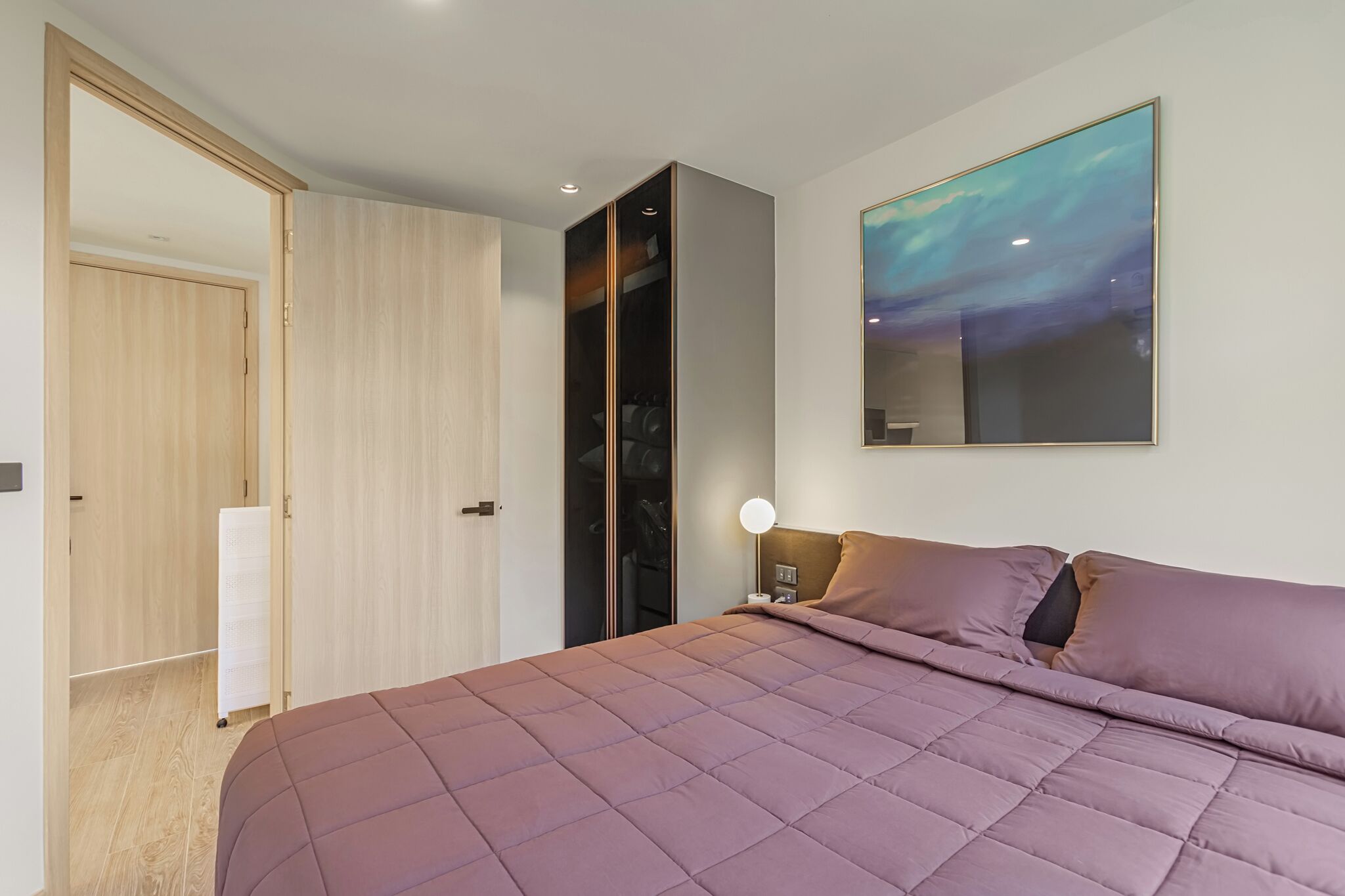 Una camera da letto moderna con un letto grande, un armadio e un comodino con una lampada.