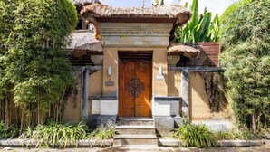 A traditional building with a wooden door, stone steps, and a thatched roof.