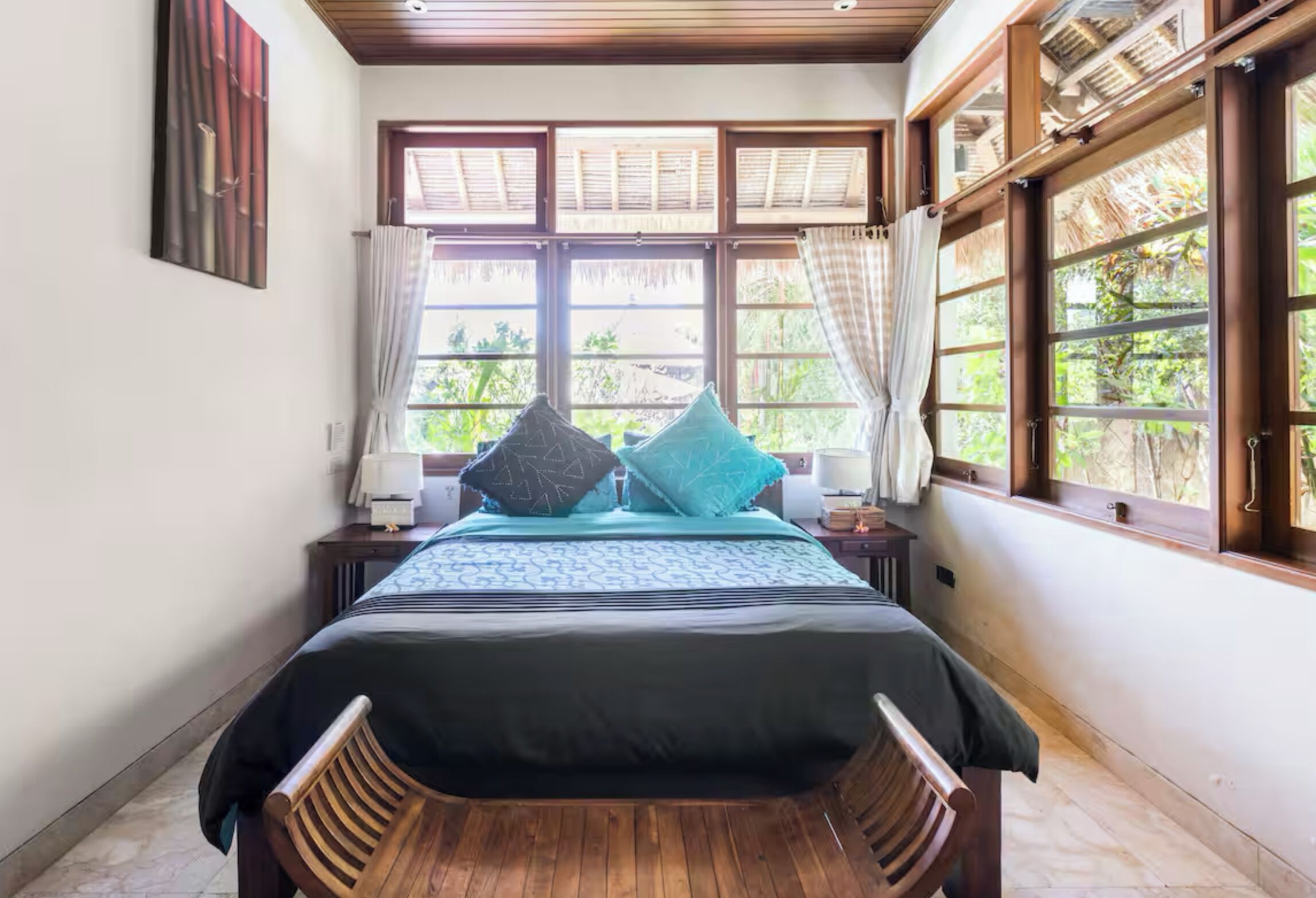 A neatly arranged bedroom with a bed, two pillows, a nightstand, and a wooden chair.