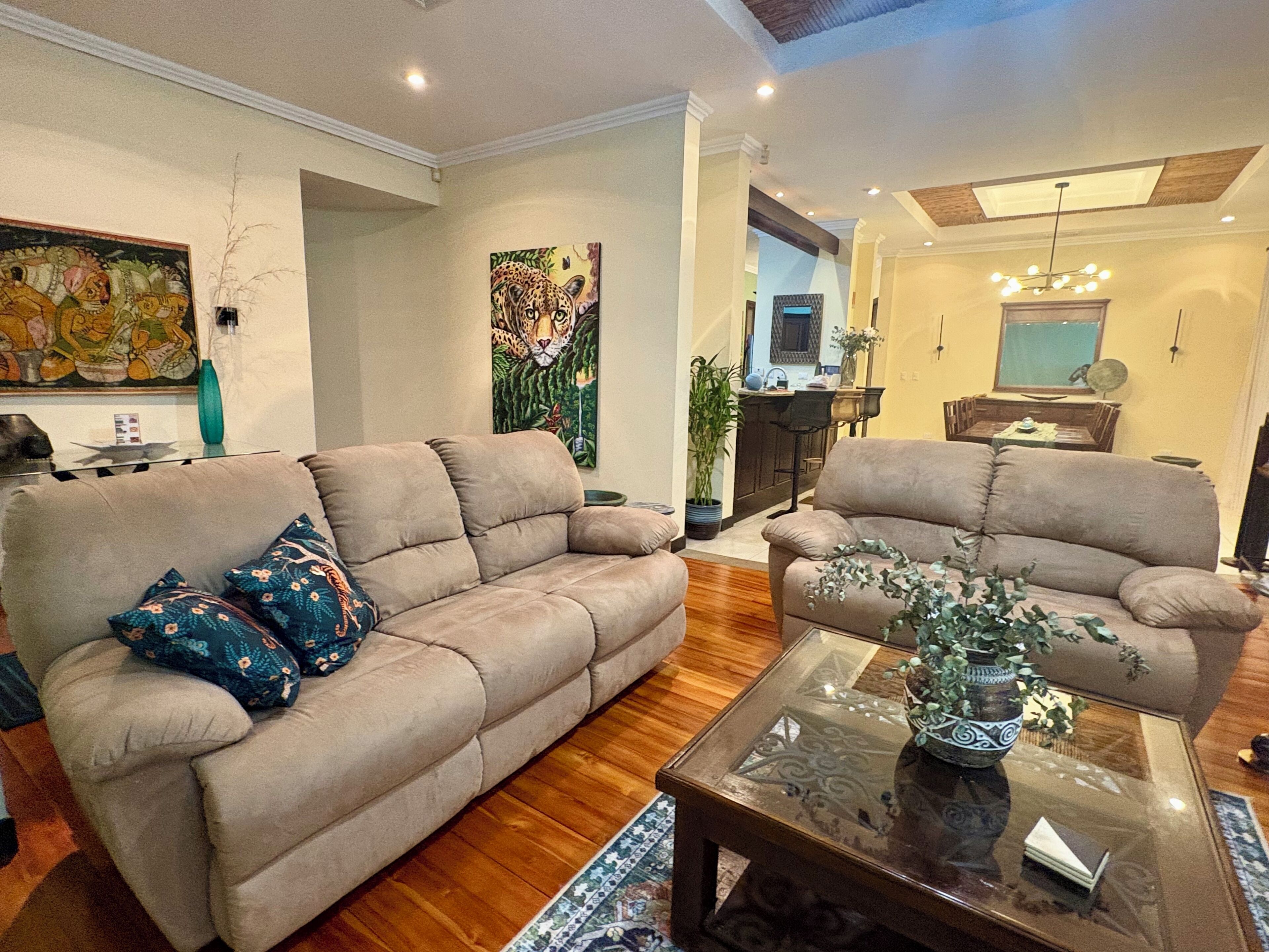 A living room with two beige sofas, a glass coffee table, and a patterned rug.