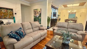 A living room with two beige sofas, a glass coffee table, and a patterned rug.