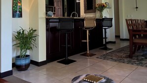 Una cocina moderna con armarios oscuros, una isla central y un comedor con una mesa redonda y sillas.