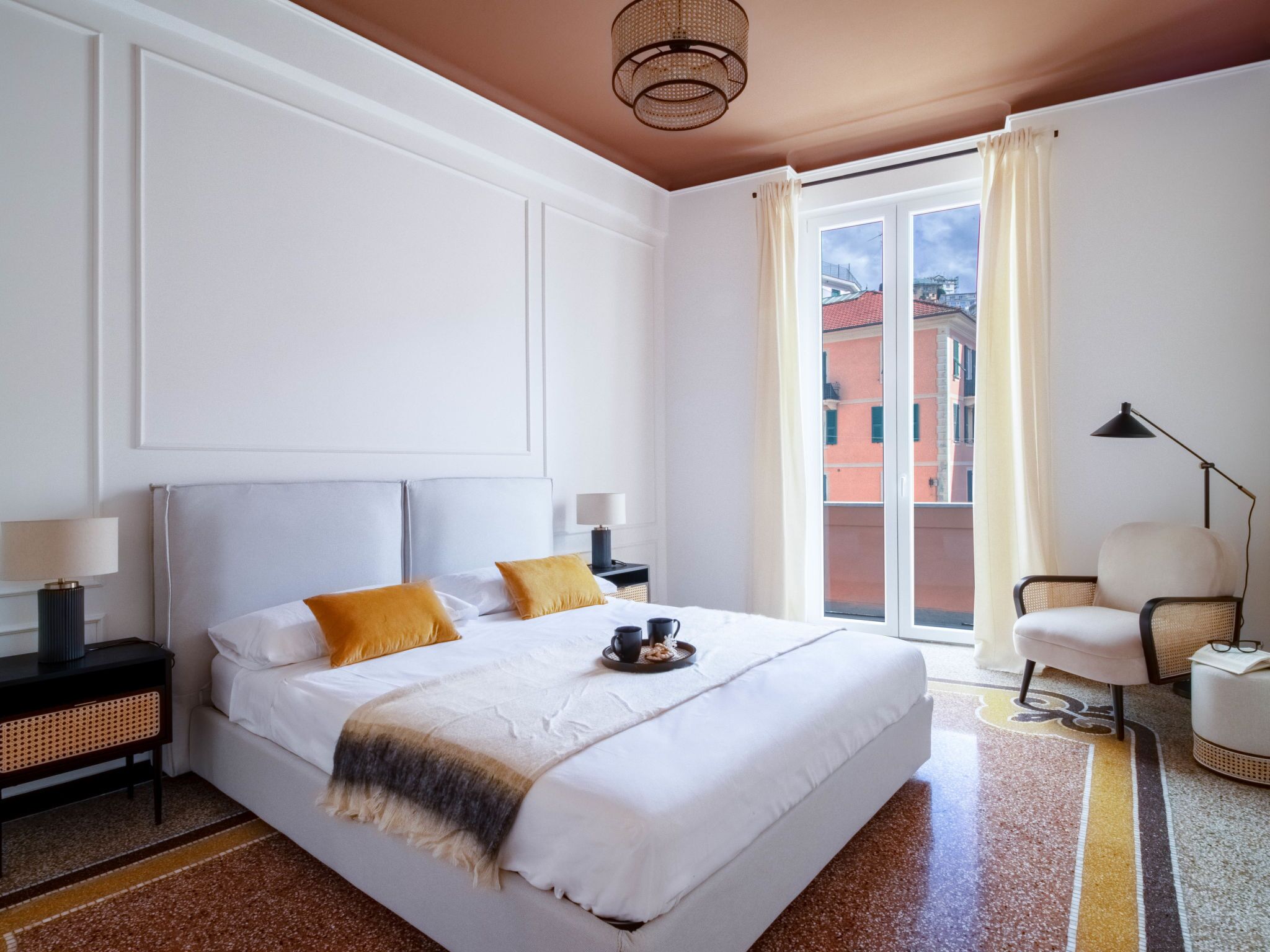 Une chambre d’hôtel avec un grand lit, une table de chevet, une chaise et une fenêtre avec des rideaux.