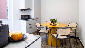 Uma cozinha moderna com armários brancos, micro-ondas e uma área de jantar com mesa redonda e quatro cadeiras.
