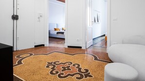 Um corredor com piso estampado que leva a um quarto com cama e mesa de cabeceira.