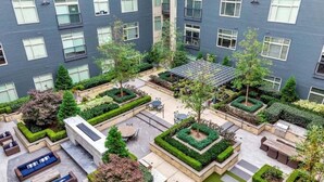 A multi-story residential building with a rooftop garden, outdoor seating areas, and a well-maintained courtyard.