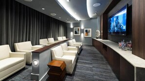 A modern cinema room with plush seating, a large screen, and a bar area.