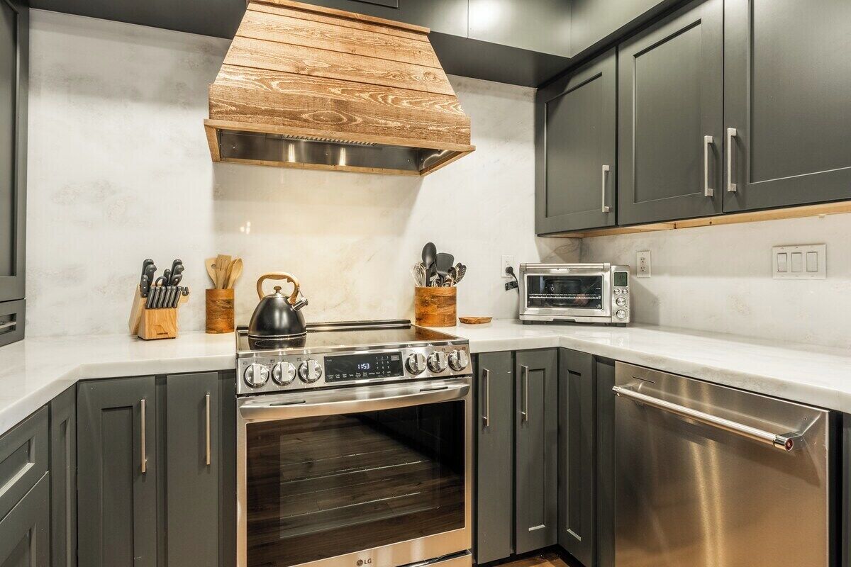 A kitchen with a stainless steel stove, microwave, and oven, wooden cabinets, and a white countertop.
