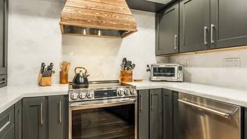 A kitchen with a stainless steel stove, microwave, and oven, wooden cabinets, and a white countertop.