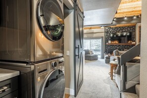A compact living space with a built-in washer and dryer, a stone fireplace, and a cozy seating area.